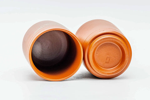 One cup tipped on its side to show the interior and foot, beside the upright second cup.