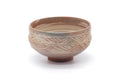 Pink-brown matcha bowl (chawan) decorated with white hakeme brushed slip and a combed lower band, three-quarter view