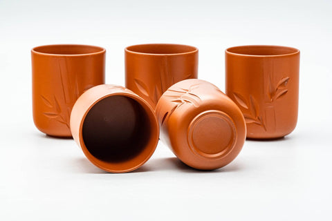 The cups grouped together, one tipped to reveal the dark glazed interior and foot.