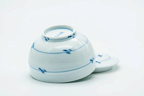 The teacup tipped to show the foot, with the lid set beside it.