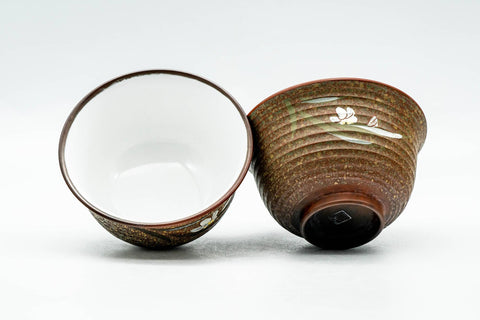 Two yunomi with one tilted to reveal the smooth white glazed interior beside the textured brown exterior