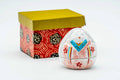 Ovoid white kogo (incense container) hand-painted with a kimono-clad woman, shown beside its decorative red-and-gold patterned box.