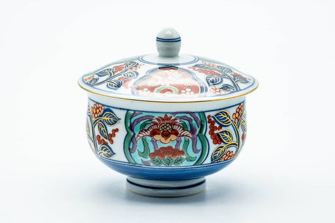 The covered yunomi with its knobbed lid in place, showing the ornate floral band.