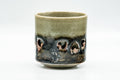 Obori Soma-yaki double-walled yunomi, front view, olive-celadon glaze with a dark band of figural decoration around the body