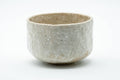 Milky-white textured matcha bowl, front view, rounded form with a coarse mottled glaze.