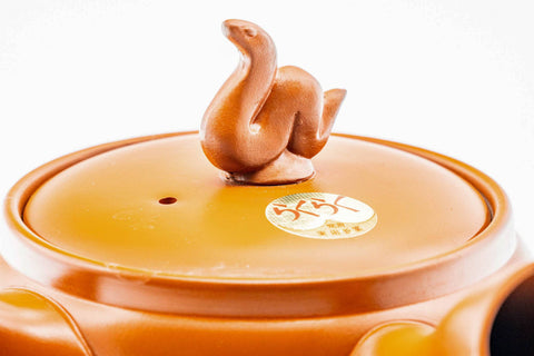 Closeup of the sculpted coiled-snake figurine forming the lid knob of the red shudei kyusu