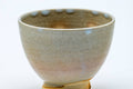 Close-up three-quarter view of one cup, showing the pale glaze with subtle tonal variation.