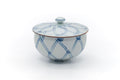 White Arita lidded teacup with a blue net-lattice pattern and brown rim, lid on, front view.