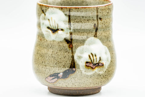 Three-quarter view of the curved yunomi with the plum-blossom decoration facing forward.