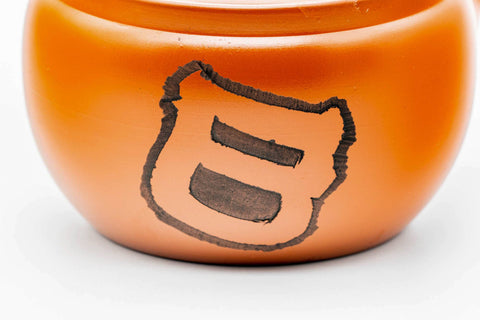 Closeup of the glossy red shudei body of the Tokoname kyusu with an engraved character motif