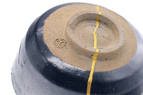 Close-up of the underside and foot ring with gold kintsugi crossing the base.