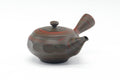 Side-handled faceted Tokoname kyusu in dark marbled clay with reddish bands, shown from a three-quarter angle.