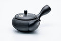 Three-quarter view of the dark kokudei Tokoname kyusu with side handle and spout, its body in a pine-bark texture