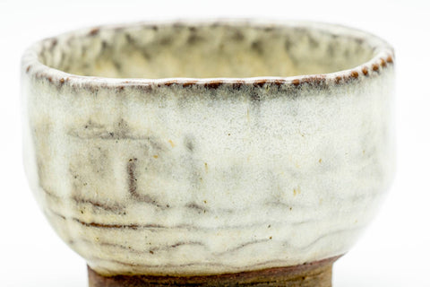 Close-up of one cup showing the milky-beige glaze with vertical brush texture and fine crackle.