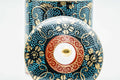 Close-up of a lid, showing the gold floral decoration and central knob.