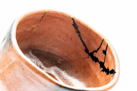 Top-down view into the bowl highlighting a dark glaze patch and gold repair.