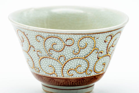 Close-up of one cup showing the red and gold scrolling vine pattern.