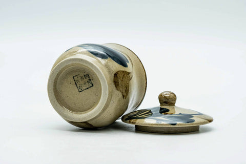 The cup on its side with the lid beside, showing the base.