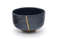 Three-quarter view showing the gold kintsugi seams over the black glaze.