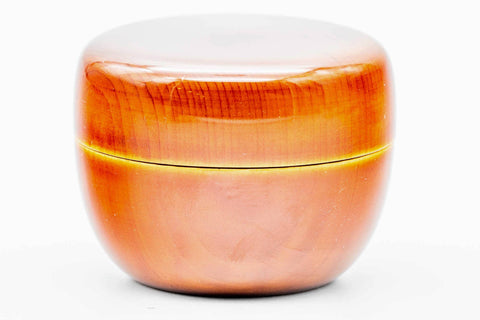 Close-up of the closed orange ko-natsume showing the glossy amber lacquer and gold band detail.