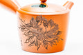 Close-up three-quarter view of the carved floral relief on the red teapot body.