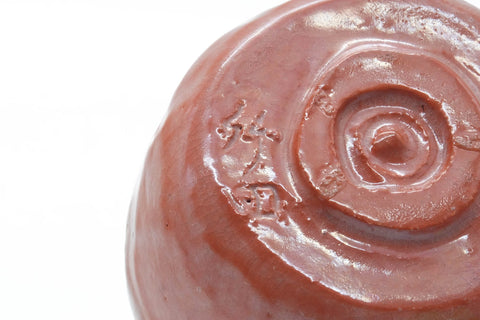 Close-up of the bowl's underside foot, showing the spiral mark in the red glaze.