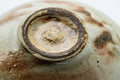 Close-up of the underside foot showing spiral throwing rings and natural clay.