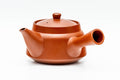 Teapot in profile showing the spout, side handle and unglazed brick-red clay