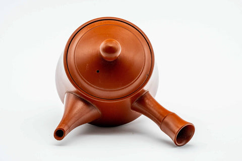Three-quarter view showing the spout and bamboo handle of the red kyusu.