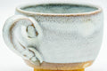 Back view of the handled cup highlighting the loop handle and glaze drips.