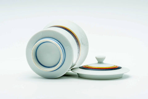 The cup on its side with the lid beside, showing the base and banded foot.