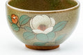 Close-up of one yunomi showing the painted white camellia over a crackled celadon glaze.