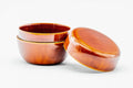 The orange ko-natsume open with the body upright showing its dark interior and the lid lying flat beside it.