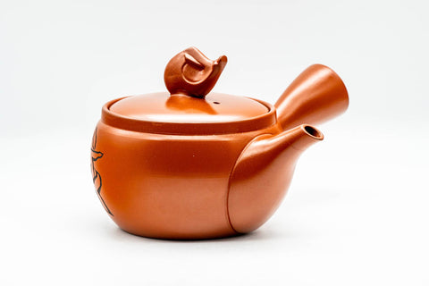 Side view of the red clay teapot showing the side handle and tapered spout, lid topped with the pig knob.
