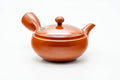 Side profile of the red clay teapot, spout to the left and hollow side handle facing the viewer.