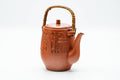 Front view of the red clay dobin showing the engraved decoration and arched top handle.
