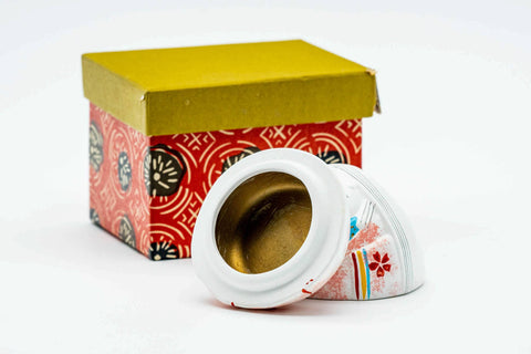 Three-quarter view with the lid lifted to reveal the gold-glazed interior, beside the box.