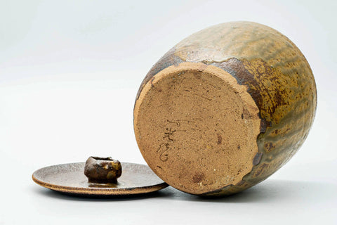 Open mizusashi lying on its side with the lid alongside, showing the small knob.