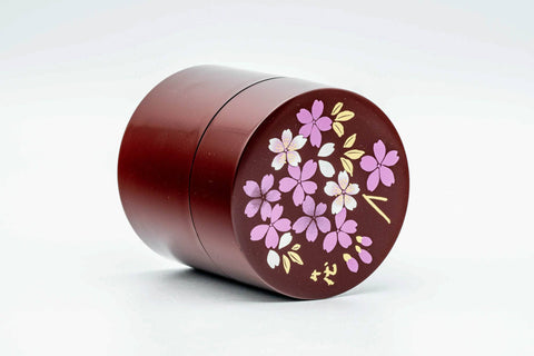 The canister with lid off, showing the blossom-decorated lid and the gold-rimmed inner lid