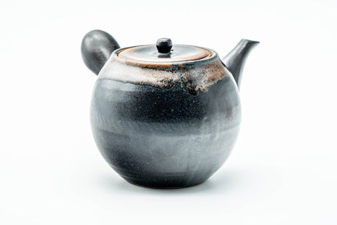 Side profile of the dark teapot, spout to the left and hollow side handle facing the viewer.
