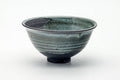 Small blue-green drip-glazed matcha bowl, front view, spiralling glaze over a compact rounded form.