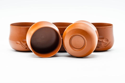 The cups grouped together, one tipped to reveal the dark glazed interior and foot.