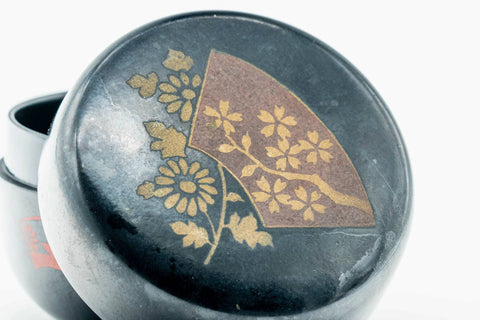 Overhead close-up of the matcha caddy lid showing the gold floral and grass maki-e design