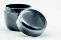 Small black-urushi ko-natsume matcha caddy, lid off, body upright with lid lying beside, three-quarter view of the interior