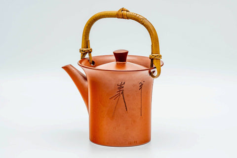 Red shudei Tokoname dobin, front view showing the engraved calligraphy and raised gold handle