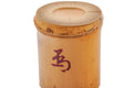 Three-quarter view from above of the bamboo futaoki, showing the open hollow top and the red character on the side.