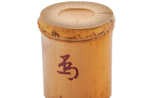 Three-quarter view from above of the bamboo futaoki, showing the open hollow top and the red character on the side.