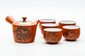 Red shudei Tokoname-yaki tea set shown from the front, with a side-handled kyusu teapot and five teacups, the teapot carved with a floral design.