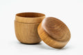 Light wooden matcha tea canister with the domed lid removed and propped against the rounded body.