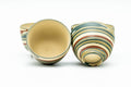 Set arrangement of the spouted water cooler and teacups revealing their interiors and the pouring spout.